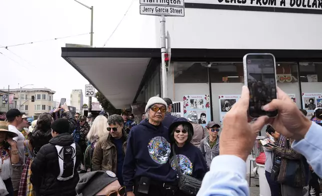 People take photographs with the Jerry Garcia Street sign after its unveiling in San Francisco, Friday, Aug. 1, 2025. (AP Photo/Godofredo A. Vásquez)