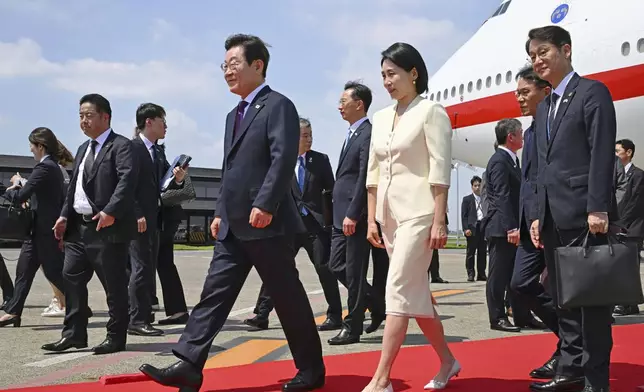 South Korean President Lee Jae Myung, center left, and his wife Kim Hea Kyung, center right, arrive at the Haneda airport in Tokyo, Japan, Saturday, Aug. 23, 2025. (Kyodo News via AP)