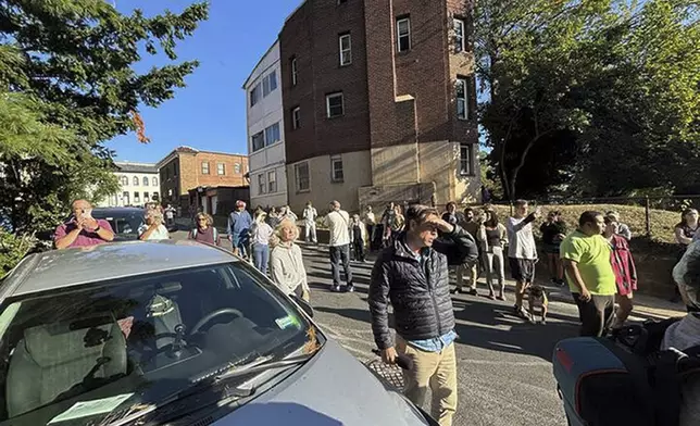 Residents from the Mount Pleasant neighborhood in Washington out in the street as Federal, and local law enforcement officer arrive to make arrest at a nearby apartment building, Wednesday, Aug. 27, 2025. (AP Photo/Collin Binkley)