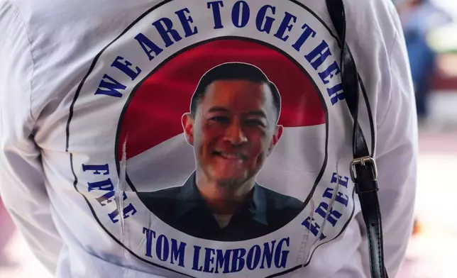 A woman supporter wearing t-shirt with a photograph of Indonesia's former Trade Minister Tom Lembong, who was sentenced to more than four years in prison stands in front of the gate of Cipinang prison in Jakarta, Indonesia, Friday, Aug. 1, 2025 as the country prepares to release hundreds of prisoners under president's clemency plan. (AP Photo/Achmad Ibrahim)