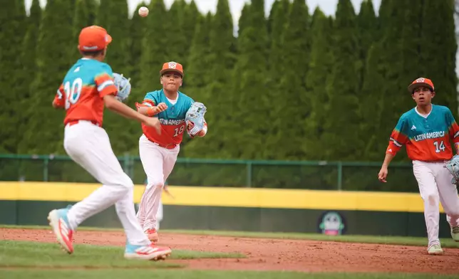 Venezuela's Fabricio Perdomo Canelon (18) tosses a ground ball to teammate Juan Reyes (10) during the sixth inning of a baseball game against Puerto Rico at the Little League World Series Wednesday, Aug. 13, 2025, in South Williamsport, Pa. (AP Photo/Jared Freed)