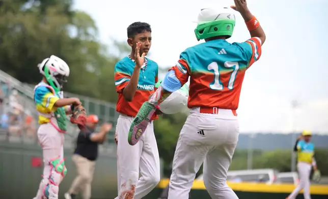 Venezuela's Alam Parra (4) celebrates a run with teammate Francisco Rivero (17) during the fifth inning of a baseball game against Puerto Rico at the Little League World Series, Wednesday, Aug. 13, 2025, in South Williamsport, Pa. (AP Photo/Jared Freed)