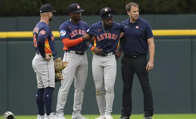 Houston Astros center fielder Taylor Trammell, second from right, is helped after being injured attempting to catch a Detroit Tigers' Dillon Dingler fly ball in the first inning during a baseball game Wednesday, Aug. 20, 2025, in Detroit. (AP Photo/Paul Sancya)