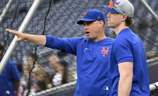 New York Mets manager Carlos Mendoza, left, talks with Brett Baty during batting practice before a baseball game against the Washington Nationals, Tuesday, Aug. 19, 2025, in Washington. (AP Photo/John McDonnell)