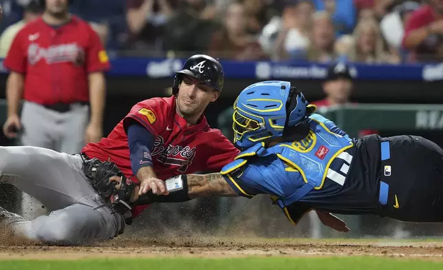 Atlanta Braves' Matt Olson, left, is tagged out by Philadelphia Phillies catcher Rafael Marchán after trying to score on a line out by Marcell Ozuna during the fifth inning of a baseball game Friday, Aug. 29, 2025, in Philadelphia. (AP Photo/Matt Slocum)