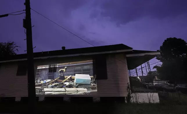This photo of a poodle perching itself precariously upon a pile of trash while surrounded by floodwaters in the aftermath of Hurricane Katrina in New Orleans, taken by AP photographer Rick Bowmer, is projected Thursday, Aug. 21, 2025, onto a house in a neighborhood that was flooded by the storm. (AP Photo/Gerald Herbert)