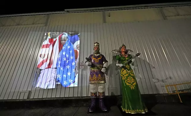 This photo of Milvertha Hendricks, 84, waiting in the rain with other flood victims outside the Ernest N. Morial Convention Center in New Orleans in the aftermath of Hurricane Katrina, taken by AP photographer Eric Gay, is projected Monday, Aug. 25, 2025, next to statues of the king and queen of Mardi Gras next to the center. (AP Photo/Gerald Herbert)