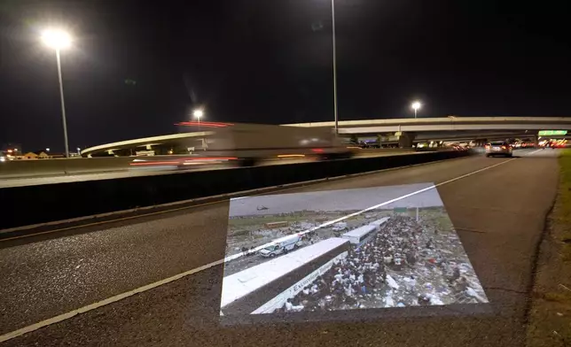 This photo showing throngs of New Orleans residents gathering at a evacuation staging area along Interstate 10 in Metairie, La., in the aftermath of Hurricane Katrina, taken by AP photographer Dave Martin, is projected Wednesday, Aug. 20, 2025, onto the same roadway. (AP Photo/Gerald Herbert)