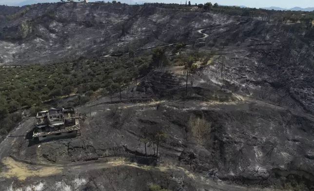 FILE - A burned house on a hill is visible from above in Kaminia seaside village, during a wildfire near Patras city, western Greece, Aug. 13, 2025. (AP Photo/Thanassis Stavrakis, File)