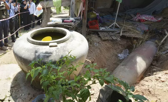 In this photo released by Agence Kampuchea Press (AKP), photographers take photos of an unexploded MK-84 bomb which Cambodian says Thai army used an F-16 aircraft to drop, in Oddar Meanchey province, Cambodia, Friday, Aug. 1, 2025. (AKP via AP)