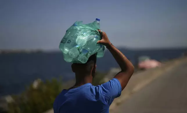 FILE - A street vendor carries plastic bottles of water on his head during a summer day in Istanbul, Thursday, July 10, 2025. (AP Photo/Francisco Seco, File)