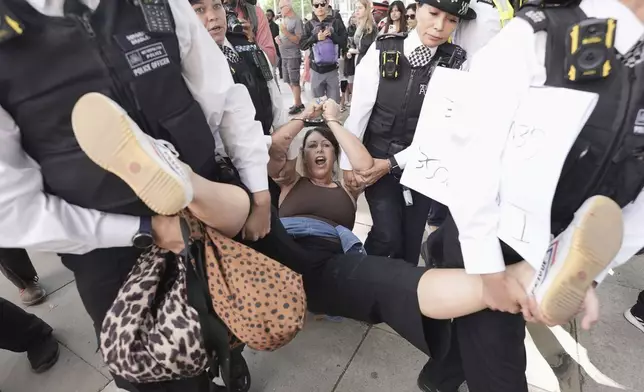 A woman is led away by police officers as supporters of Palestine Action take part in a mass action in Parliament Square, organised by Defend Our Juries as part of the Lift the Ban campaign, to end the proscription of Palestine Action, in London, Saturday, Aug. 9, 2025. (Stefan Rousseau/PA via AP)