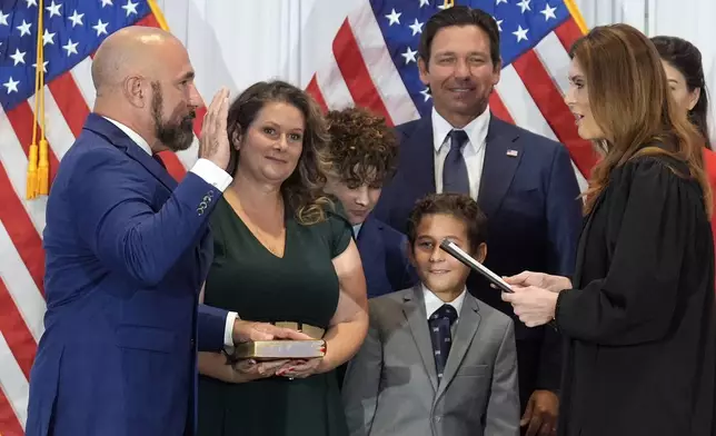 Florida Sen. Jay Collins, (R-District 14) left, surrounded by family members and Governor Ron DeSantis, takes the oath of office after being named the new Lieutenant Governor of Florida during a news conference Tuesday, Aug. 12, 2025, in Tampa, Fla. (AP Photo/Chris O'Meara)