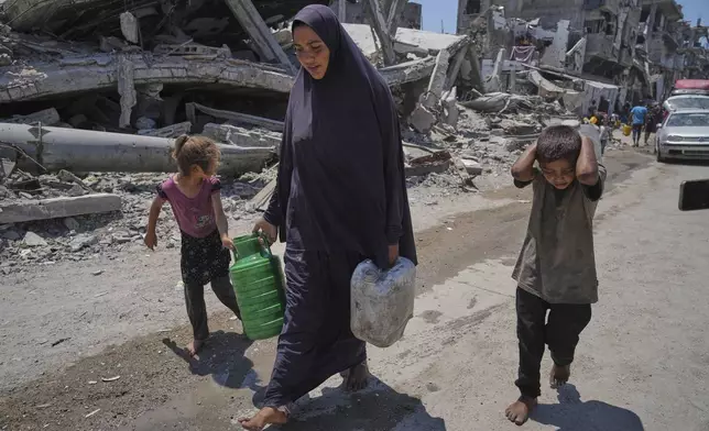 Abeer Sobh and her children carry water in plastic jerrycans after collecting it from a water truck in Gaza City, Thursday, July 24, 2025. (AP Photo/Jehad Alshrafi)
