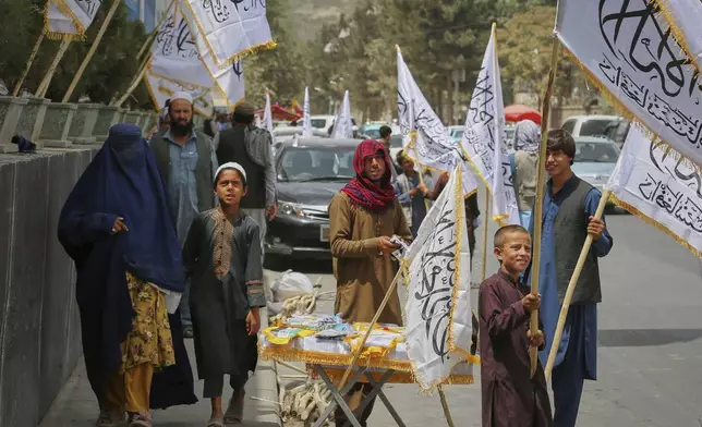A man sells Taliban flags at a stand ahead of celebrations marking the fourth anniversary of the U.S. withdrawal from Afghanistan and the start of Taliban rule, in Kabul, Afghanistan, Thursday, Aug. 14, 2025. (AP Photo/Siddiqullah Alizai)