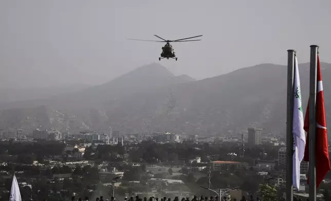 A military helicopter drops flowers over the city during celebrations marking the fourth anniversary of the U.S. withdrawal and the start of Taliban rule in Kabul, Afghanistan, Friday, Aug. 15, 2025. (AP Photo/Siddiqullah Alizai)