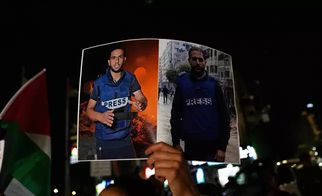 A woman carries a poster showing Palestinian journalists Anas al-Sharif, left, and Mohamed Qreiqeh that Israel's military targeted and killed with an airstrike late Sunday in Gaza, during a protest in the West Bank city of Ramallah Monday, Aug. 11, 2025. (AP Photo/Nasser Nasser)