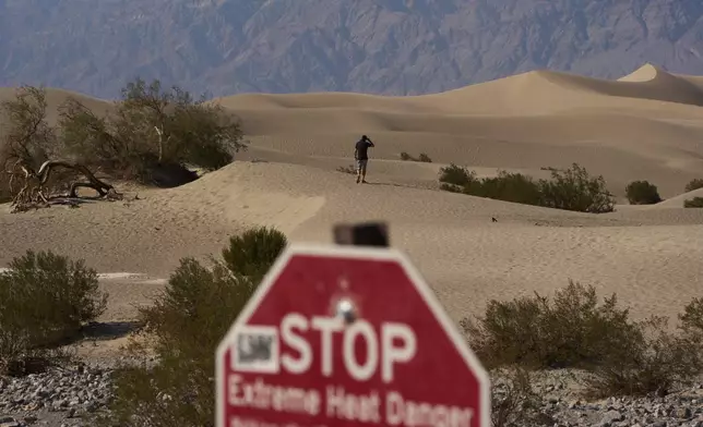 A person walks on sand dunes Sunday, Aug. 3, 2025, in Death Valley National Park, Calif. (AP Photo/John Locher)