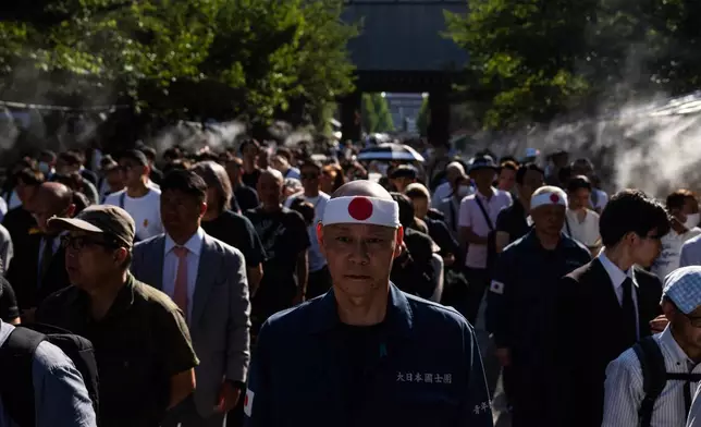 Visitors line up to offer prayers at the Yasukuni Shrine on the 80th anniversary of Japan's surrender in World War II, in Tokyo, Friday, Aug. 15, 2025. (AP Photo/Louise Delmotte)