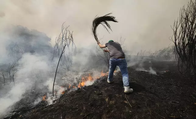 A man battles a wildfire in Veiga das Meas, northwestern Spain, Saturday, Aug. 16, 2025. (AP Photo/Lalo R. Villar)