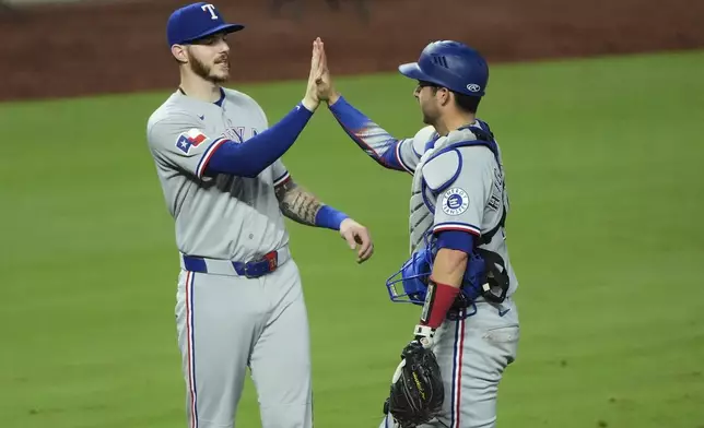 Texas Rangers' Jonah Heim, left, and Kyle Higashioka celebrate after their baseball game against the Kansas City Royals, Wednesday, Aug. 20, 2025, in Kansas City, Mo. (AP Photo/Charlie Riedel)
