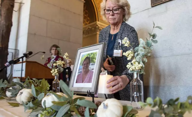FILE - Tracy Wodatch, from Connecticut Association for Healthcare at Home, places a candle next to a photo of Joyce Grayson at a vigil for Grayson at the Connecticut Capitol's North Lobby, Nov. 28, 2023, in Hartford, Conn. (Aaron Flaum/Hartford Courant via AP, File)