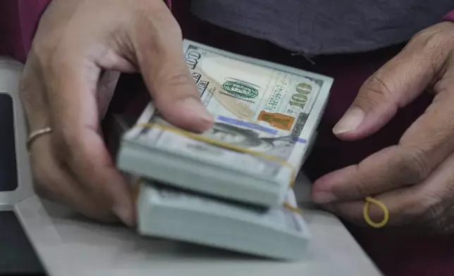 An employee holds U.S. dollar notes at a money changer in Jakarta, Indonesia, Thursday, Aug. 7, 2025. (AP Photo/Tatan Syuflana)