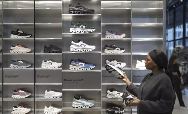 FILE - An employee at On tidies up sports shoes from the On sports brand in the On store on Wednesday, Jan. 22, 2025, at On's headquarters in Zurich. (Gaetan Bally/Keystone via AP)