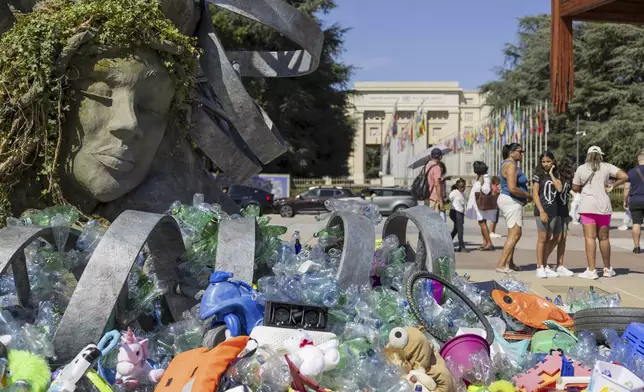 Plastic items are seen next to an artwork by Canadian artist and activist Benjamin Von Wong, titled 'The Thinker's Burden', a 6-meter-tall sculptural remix of Rodin's iconic Thinker, created especially for the Plastics Treaty negotiations, on Place des Nations in front of the European headquarters of the United Nations in Geneva, Switzerland, Monday, Aug. 4, 2025 before the second segment of the fifth session of the Intergovernmental Negotiating Committee on Plastic Pollution (INC-5.2). (Salvatore Di Nolfi/Keystone via AP)