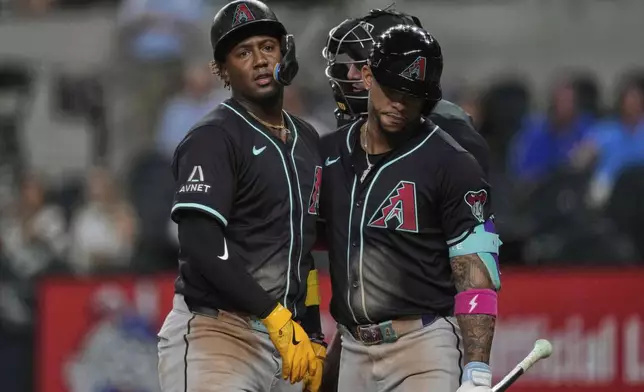 Arizona Diamondbacks' Ketel Marte, right, escorts Geraldo Perdomo away from the home plate after Perdomo began arguing with umpire Nate Tomlinson, rear, after being called out on strikes in the ninth inning of a baseball game against the Texas Rangers Tuesday, Aug. 12, 2025, in Arlington, Texas. (AP Photo/Tony Gutierrez)