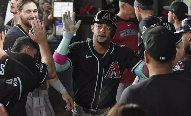 Arizona Diamondbacks second baseman Ketel Marte, center, celebrates in the dugout after hitting a solo home run in the ninth inning of a baseball game against the Texas Rangers Tuesday, Aug. 12, 2025, in Arlington, Texas. (AP Photo/Tony Gutierrez)