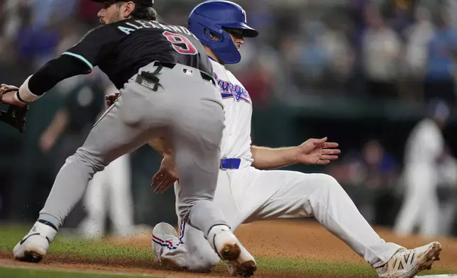Texas Rangers' Josh Smith advances to third on a sacrifice fly by Marcus Semien as Arizona Diamondbacks third baseman Blaze Alexander waits on the throw to the bag in the third inning of a baseball game Tuesday, Aug. 12, 2025, in Arlington, Texas. (AP Photo/Tony Gutierrez)