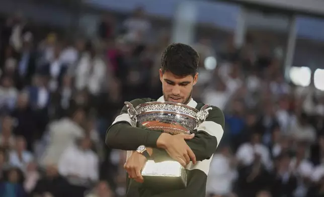 FILE - Spain's Carlos Alcaraz celebrates with the trophy after winning the final match of the French Tennis Open against Italy's Jannik Sinner at the Roland-Garros stadium in Paris, June 8, 2025. (AP Photo/Thibault Camus, File)