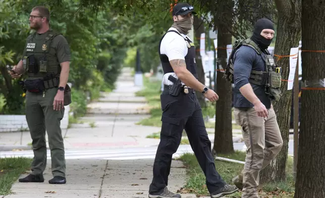 Armed officers from several federal agencies including U.S. Marshals, FBI, HSI, and Park Police, leave an apartment complex after arresting a man from within the apartment complex, Tuesday, August 19, 2025, in the Petworth neighborhood of northwest Washington. (AP Photo/Jacquelyn Martin)