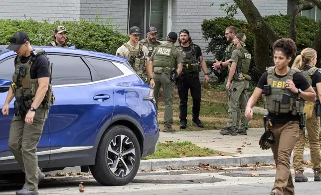 Officers from several federal agencies including FBI, Federal Marshalls, HSI, and Park Police, leave an apartment complex after arresting a man from within the apartments, Tuesday, Aug. 19, 2025, in the Petworth neighborhood of northwest Washington. (AP Photo/Jacquelyn Martin)