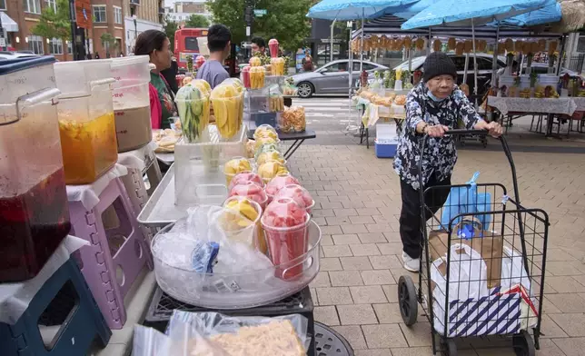 A woman walks past fruit vendors without buying anything, Tuesday, Aug. 19, 2025, as vendors wait for customers in the Columbia Heights neighborhood of northwest Washington. (AP Photo/Jacquelyn Martin)