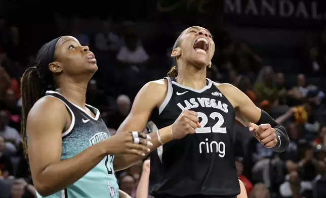 Las Vegas Aces center A'ja Wilson (22) celebrates by New York Liberty forward Kennedy Burke after making a basket and drawing a foul during the first half of a WNBA basketball game, Wednesday, Aug. 13, 2025, in Las Vegas. (Steve Marcus/Las Vegas Sun via AP)