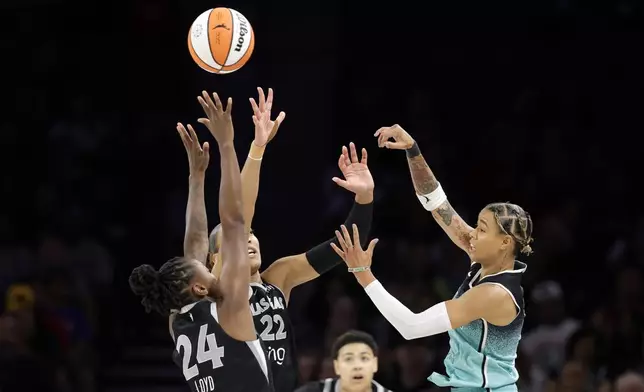 New York Liberty guard Natasha Cloud passes over Las Vegas Aces guard Jewell Loyd (24) and center A'ja Wilson (22) during the first half of a WNBA basketball game, Wednesday, Aug. 13, 2025, in Las Vegas. (Steve Marcus/Las Vegas Sun via AP)