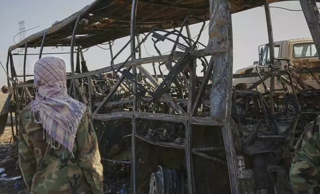 A man looks at a burned-out bus that collided with a truck and a motorbike Tuesday evening, causing a massive fire and killing at least 70 people, including children, most of them Afghans returning from Iran, in western Herat province, Afghanistan, Wednesday, Aug. 20, 2025. (AP Photo/Omid Haqjoo)