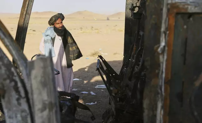 A man looks at a burned-out bus that collided with a truck and a motorbike Tuesday evening, causing a massive fire and killing at least 70 people, including children, most of them Afghans returning from Iran, in western Herat province, Afghanistan, Wednesday, Aug. 20, 2025. (AP Photo/Omid Haqjoo)