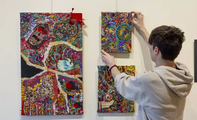 Briar Townes, a senior at Perry Central High School, straightens a piece of his art on display at the Arts Council for Wyoming County, on March 12, 2025, in Perry, N.Y. (AP Photo/Lauren Petracca)