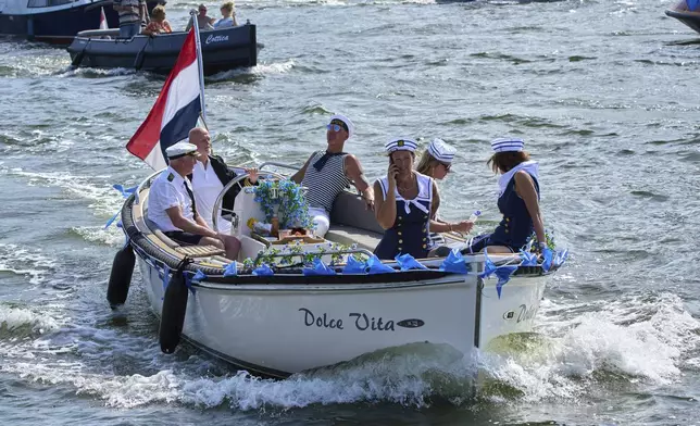 People dressed in sailor costumes watch hundreds of tall ships sail into the Dutch capital's harbor for the 10th edition of SAIL, in Amsterdam, Netherlands, Wednesday, Aug. 20, 2025. (AP Photo/Peter Dejong)