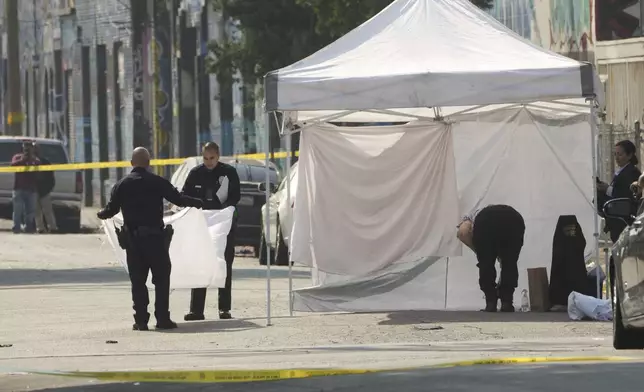 Police remove white sheets after Los Angeles County Coroner removed victims of a mass shooting during a music festival after-party in downtown Los Angeles, Monday, Aug. 4, 2025. (AP Photo/Damian Dovarganes)