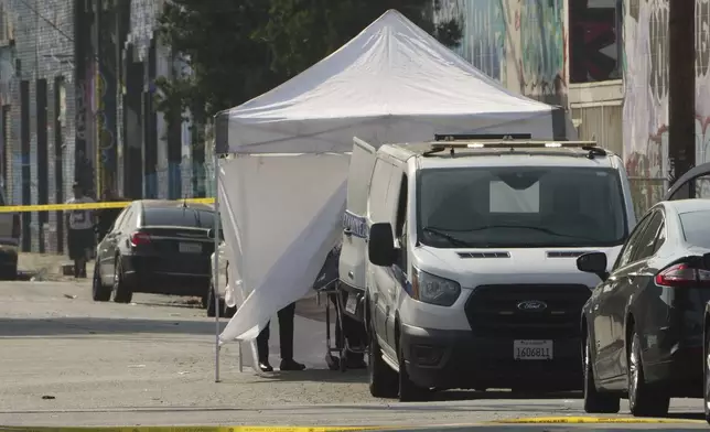 Los Angeles County Coroner van remove a shooting victims' body covered by a white tent after a mass shooting during a music festival after-party in downtown Los Angeles, Monday, Aug. 4, 2025. (AP Photo/Damian Dovarganes)