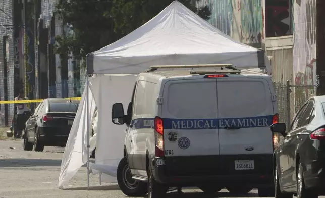 Los Angeles Coroner Medical Examiner arrives to remove the bodies of victims after a mass shooting during a music festival after-party in downtown Los Angeles, Monday, Aug. 4, 2025. (AP Photo/Damian Dovarganes)