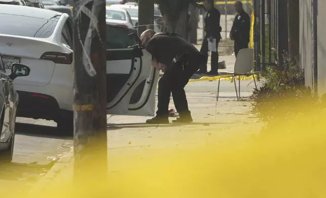 A police photographer documents a vehicle next to the scene of a mass shooting during a music festival after-party in downtown Los Angeles, Monday, Aug. 4, 2025. (AP Photo/Damian Dovarganes)