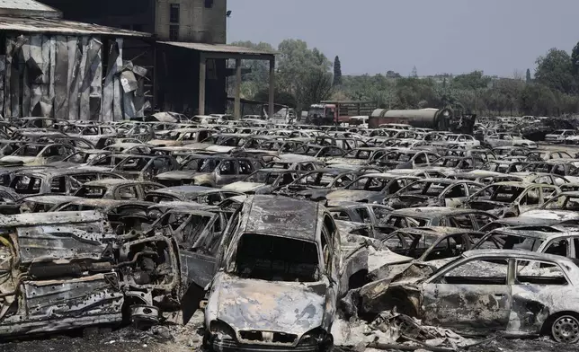 Burned cars are seen at an impound lot in Kato Achaia, during a wildfire near Patras city, western Greece, Wednesday, Aug. 13, 2025. (AP Photo/Thanassis Stavrakis)