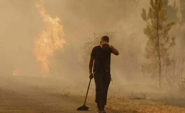 A volunteer reacts in front of a wildfire in Larouco, northwestern Spain, Wednesday, Aug. 13, 2025. (AP Photo/Lalo R. Villar)