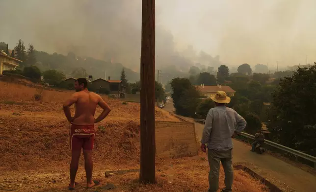 People watch a wildfire in Vounteni village, on the outskirts of Patras, western Greece, Wednesday, Aug. 13, 2025. (AP Photo/Thanassis Stavrakis)