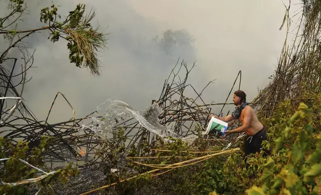 A man tries to control the fire during a wildfire in Vounteni, on the outskirts of Patras, western Greece, Wednesday, Aug. 13, 2025. (AP Photo/Thanassis Stavrakis)